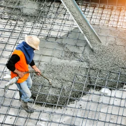 Top view of builders in orange shirt pouring concrete works on the construction site