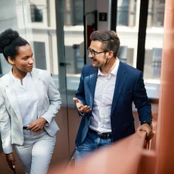 Happy colleagues talking while walking up the stairs in office.